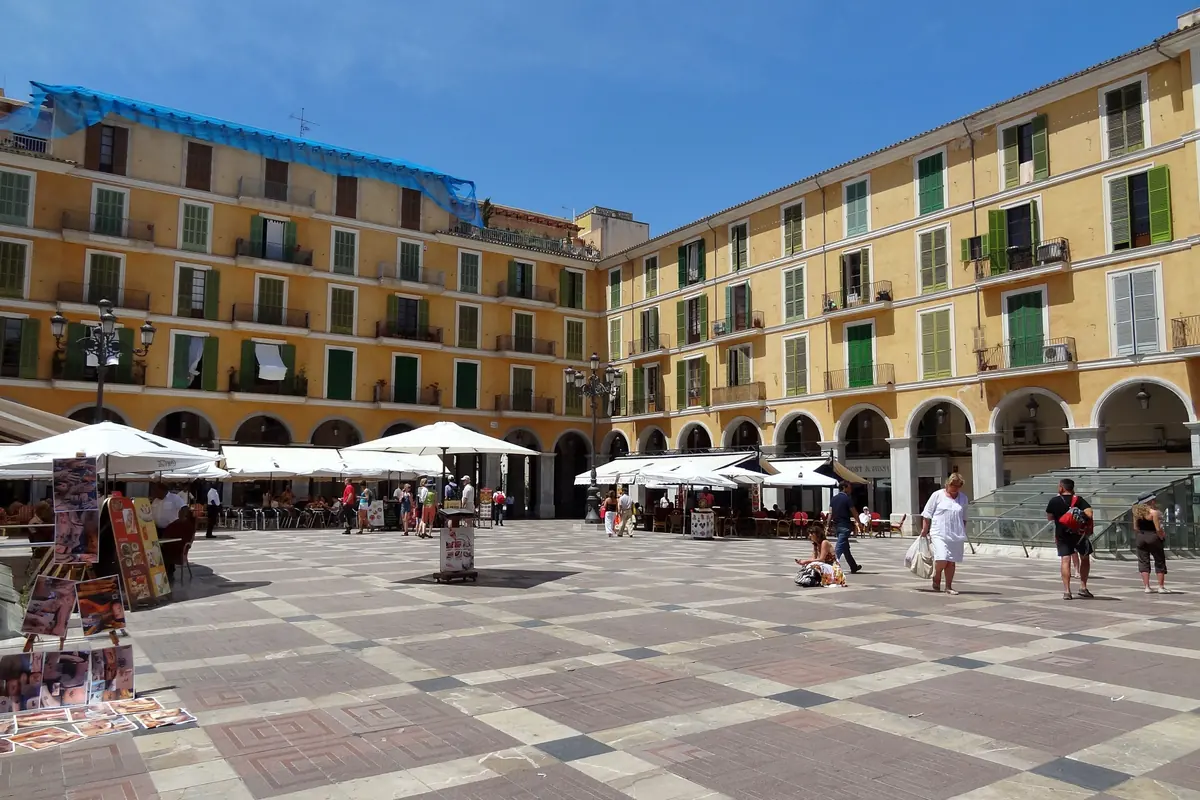 Cafe umbrellas in the arcaded Plaça Major in the centre of Palma, under a blue sky
